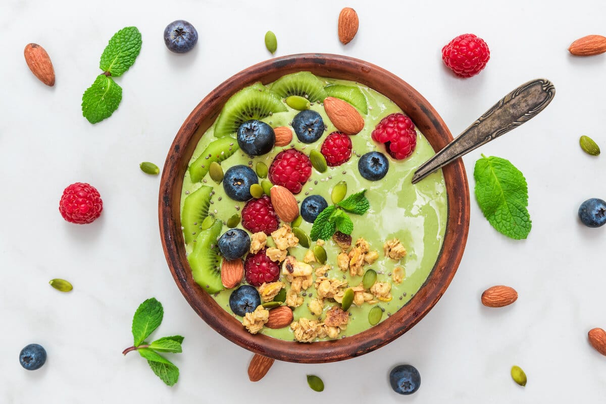 Bowl of green smoothie with fruits and nuts