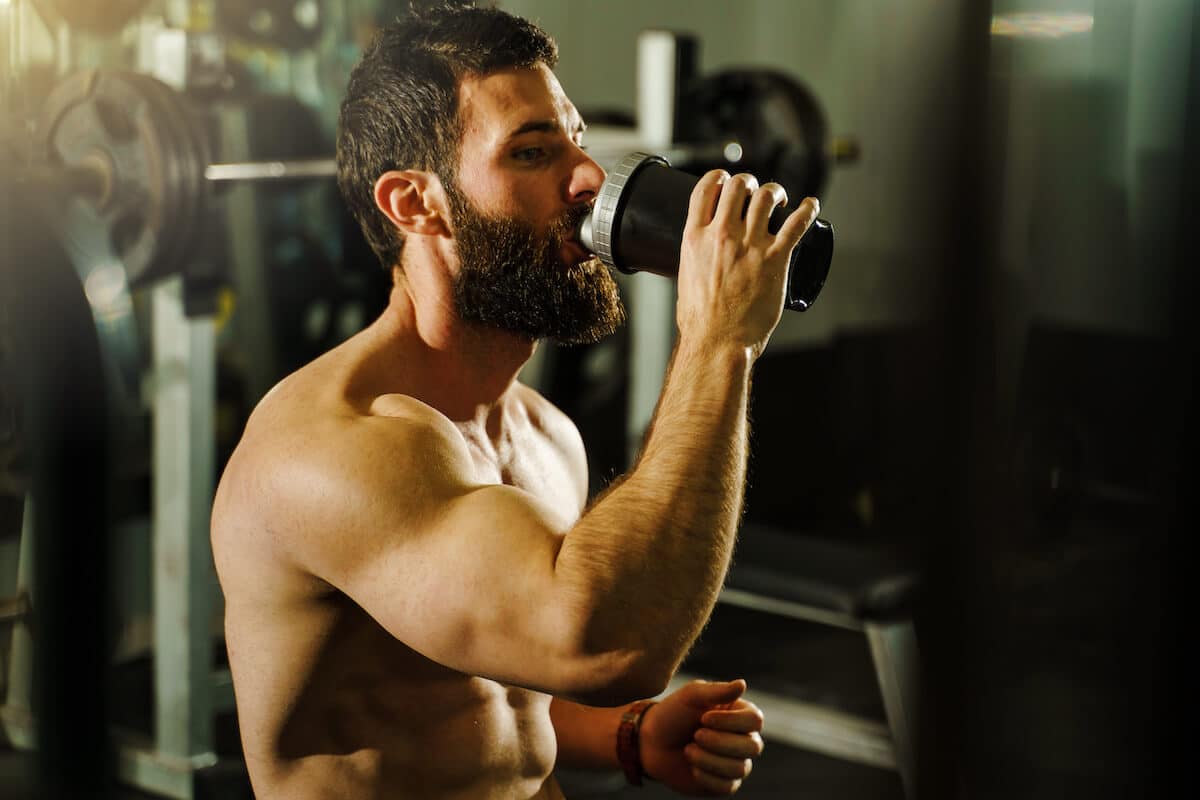When to take amino acids: athletic man drinking from a tumbler