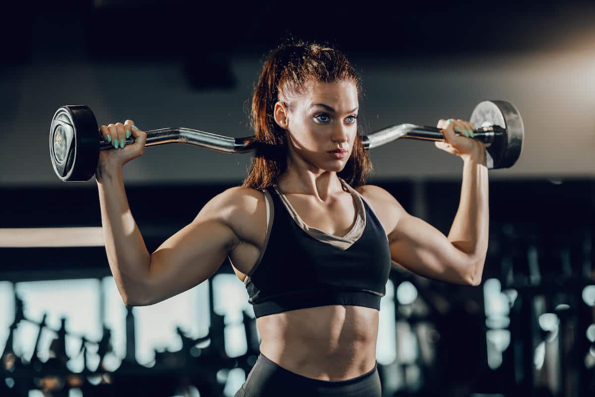 Muscle recovery supplements: woman lifting a barbell