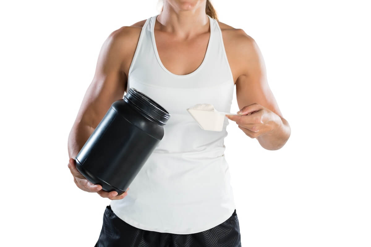 Are BCAAS worth it: athlete taking a scoop of protein powder