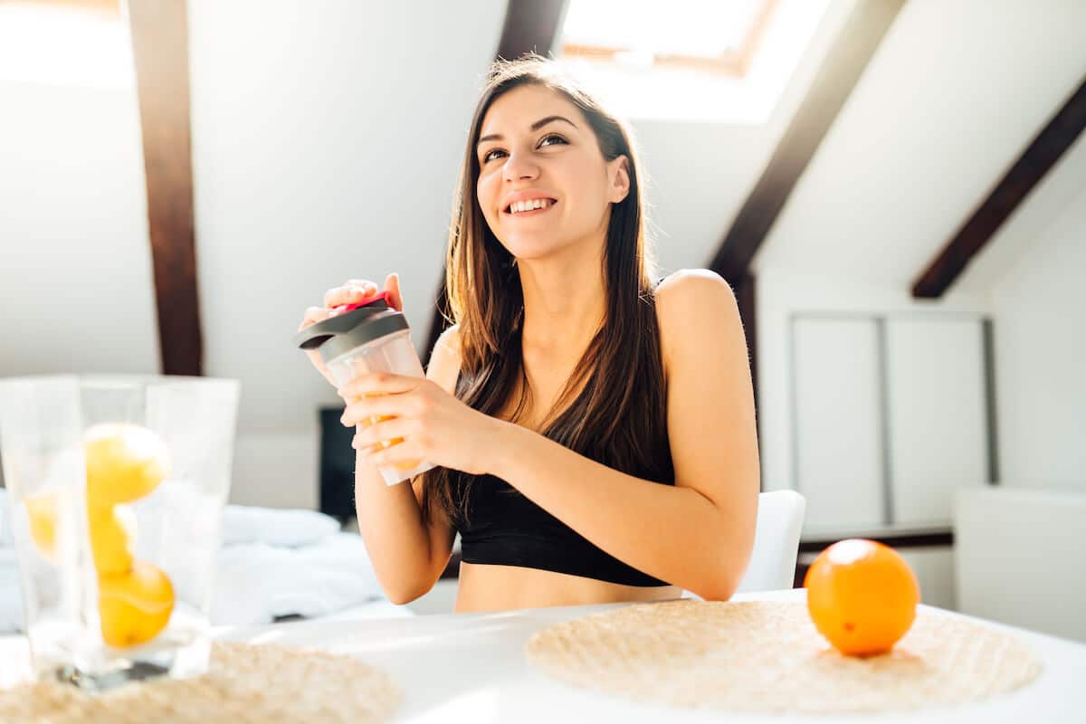 Post workout supplements: happy woman holding a tumbler