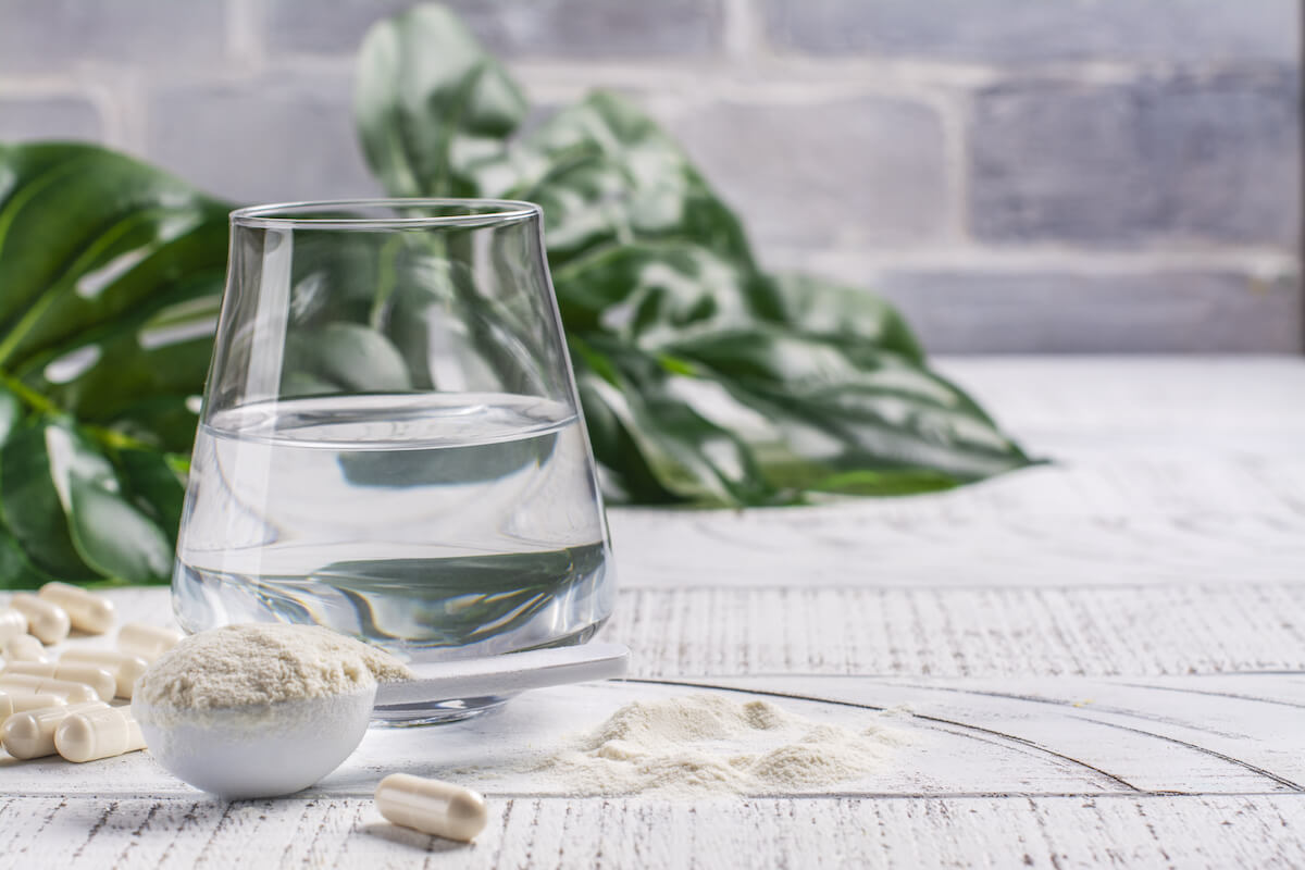 Collagen powder and pills beside a glass of water