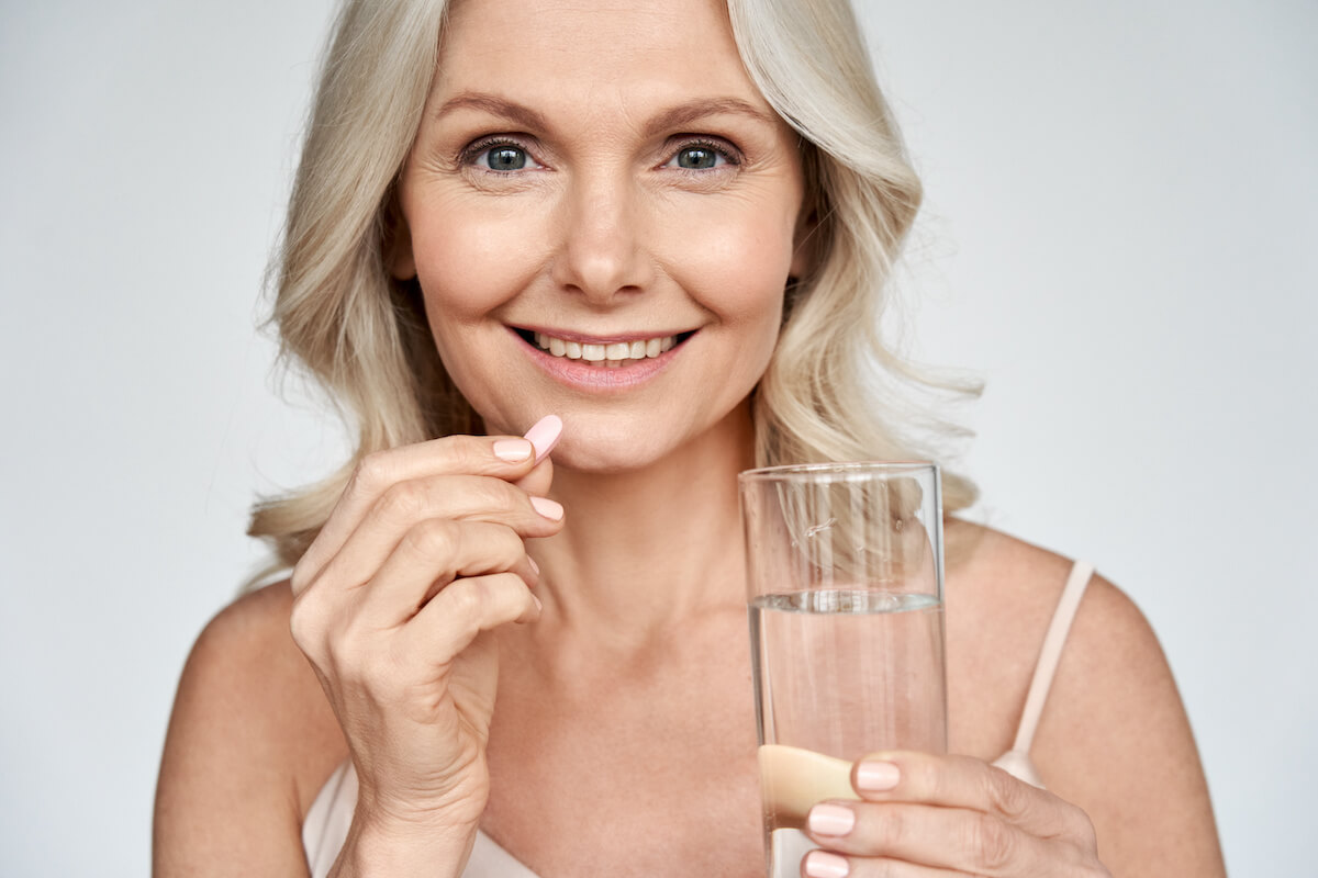 Best supplements for women: happy woman about to drink a pill
