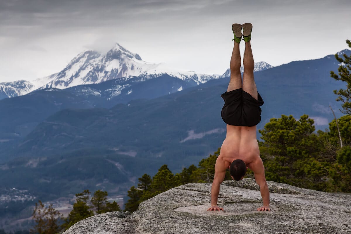Calisthenics vs weights: man doing a handstand on a cliff