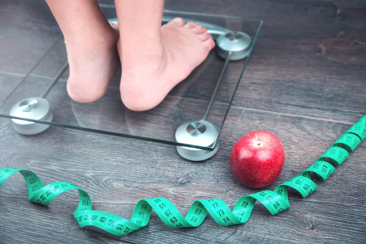How often should you eat: person on a scale, an apple on the floor and a measuring tape