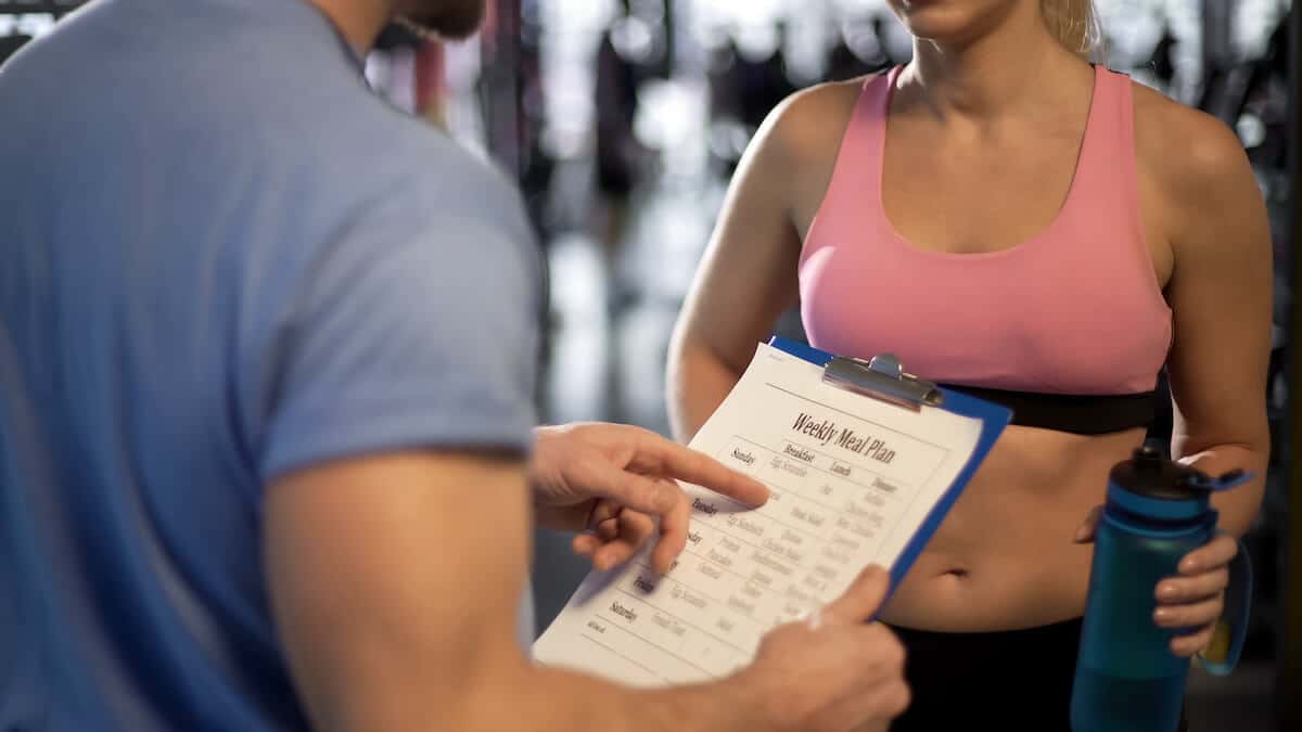 How often should you eat: trainer holding a weekly meal plan