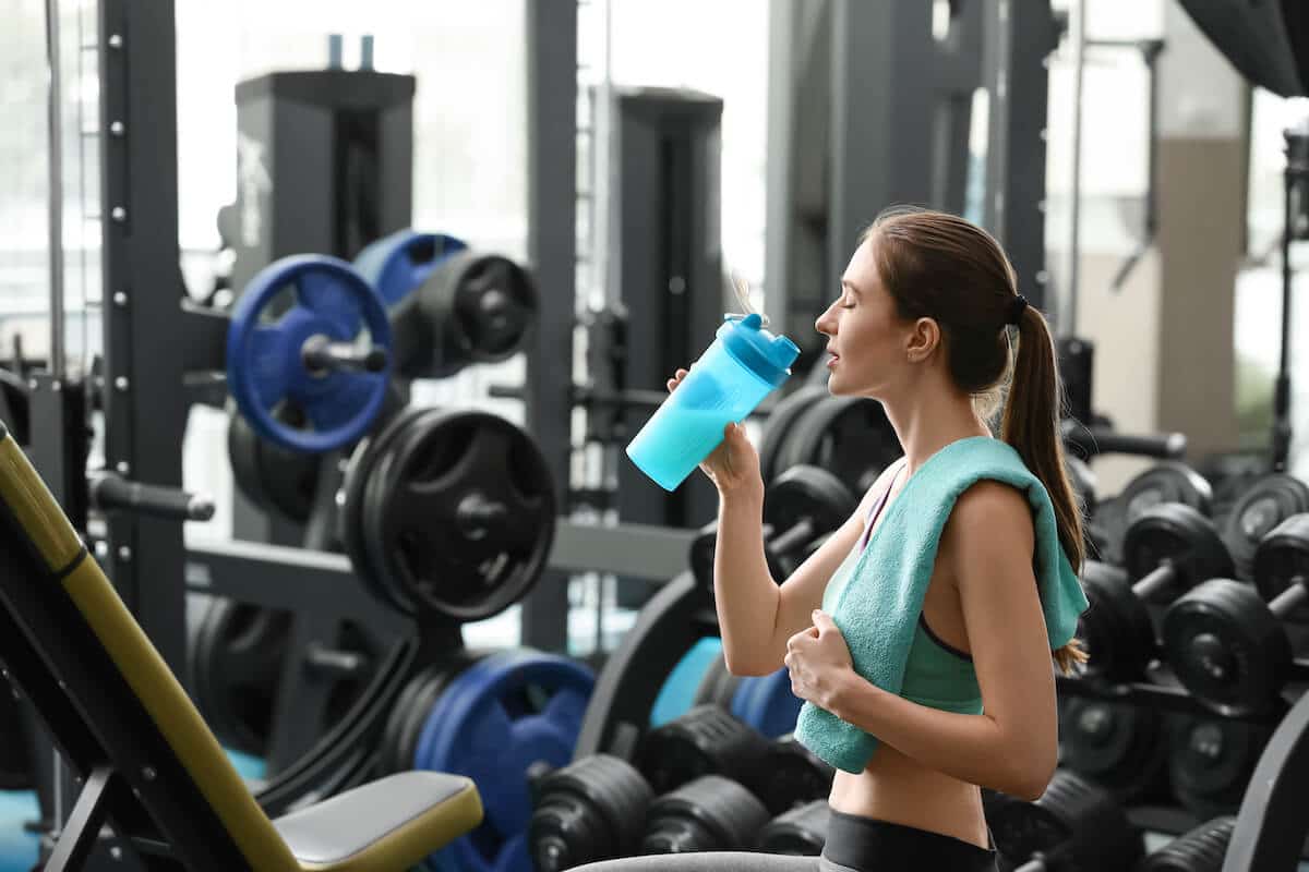 How much protein after workout: woman drinking a protein shake at the gym