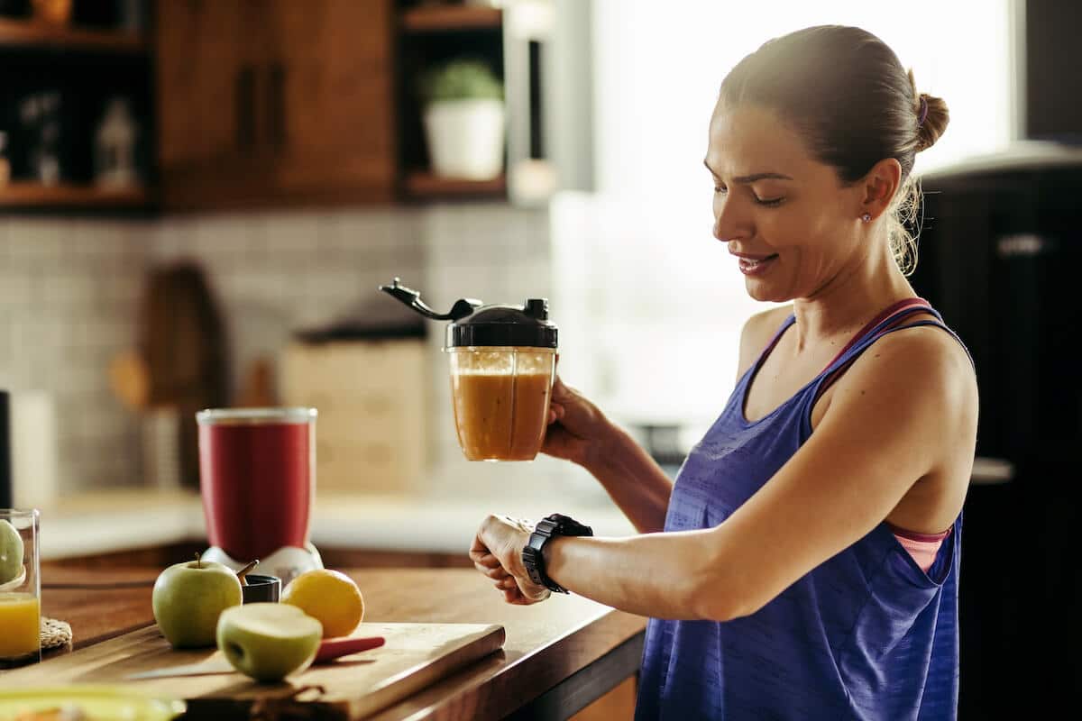 Woman holding a smoothie while checking the time