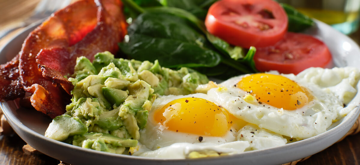 High protein low carb meals: eggs, bacon, tomatoes and avocados on a plate