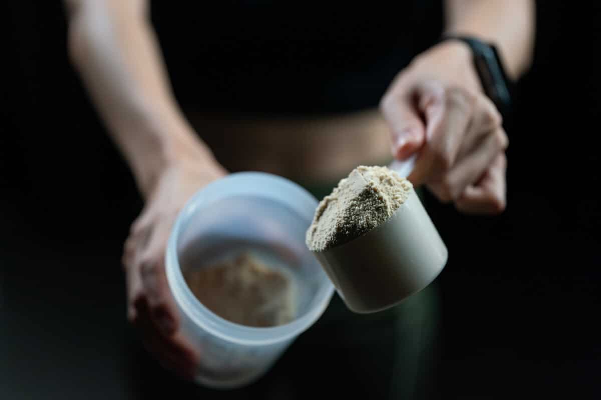 Person pouring protein powder into a tumbler