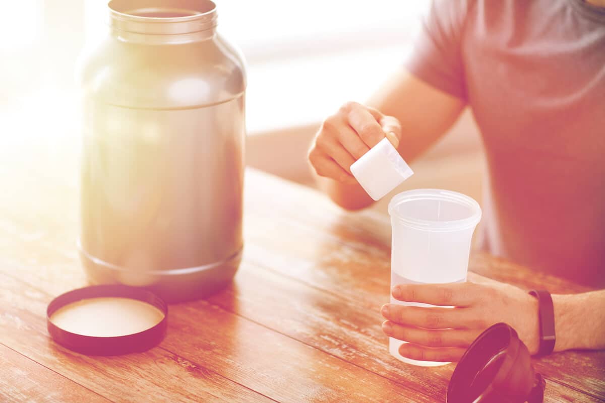 Is pea protein good for you: person pouring protein powder into a tumbler