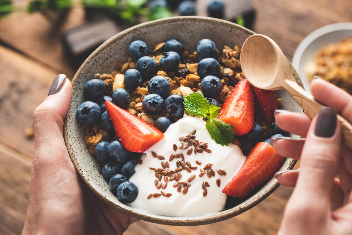 High protein vegan snacks: bowl of granola with yogurt, blueberries and strawberries