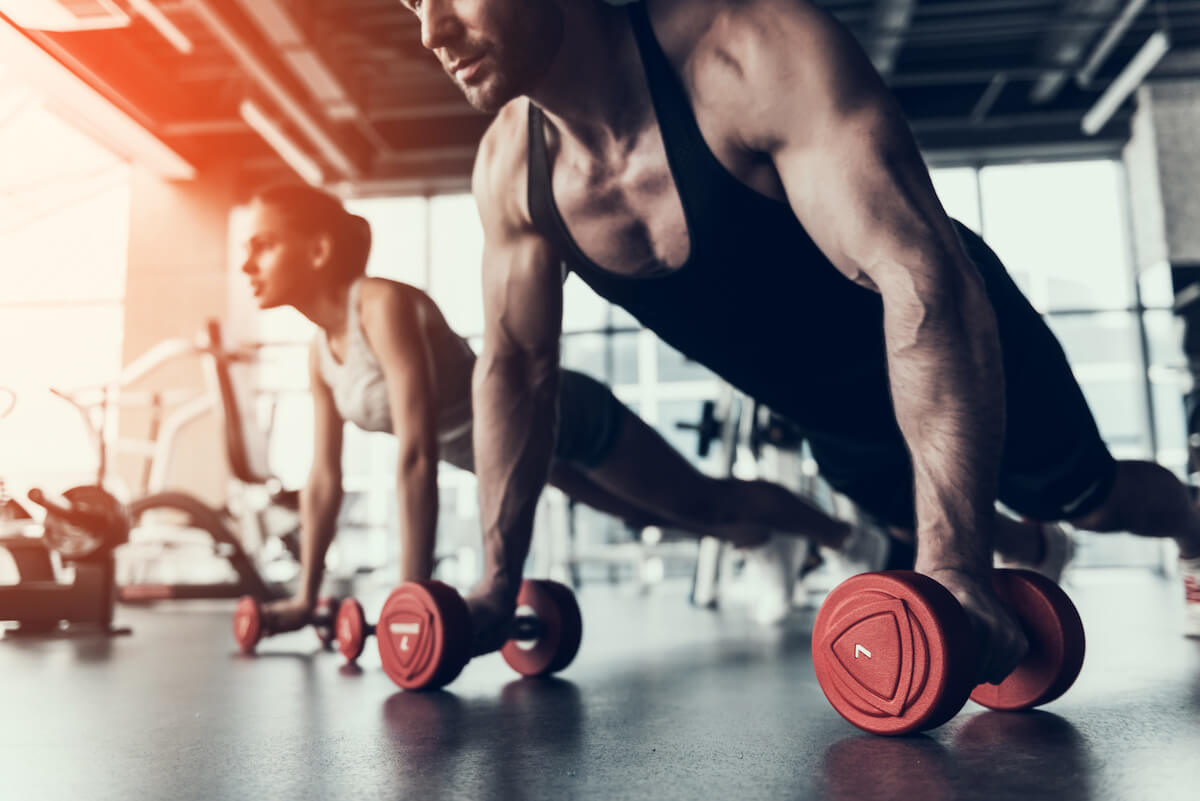 Metabolic conditioning: man and woman doing planks with dumbbells