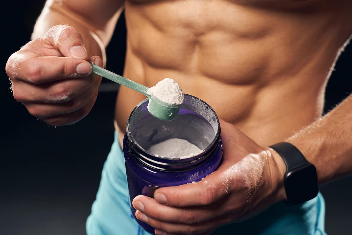 Types of protein powder: bodybuilder scooping protein powder from a jar