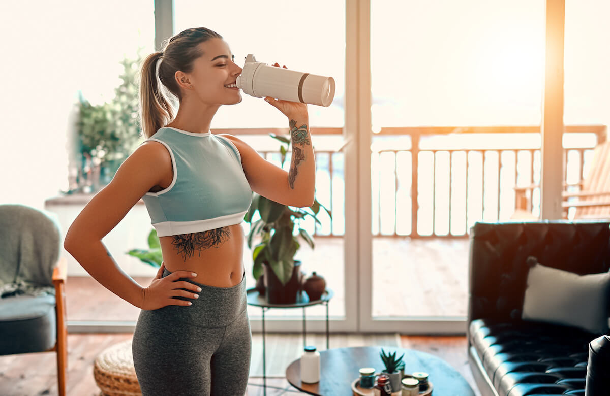 Protein shake for breakfast: woman happily drinking from her tumbler