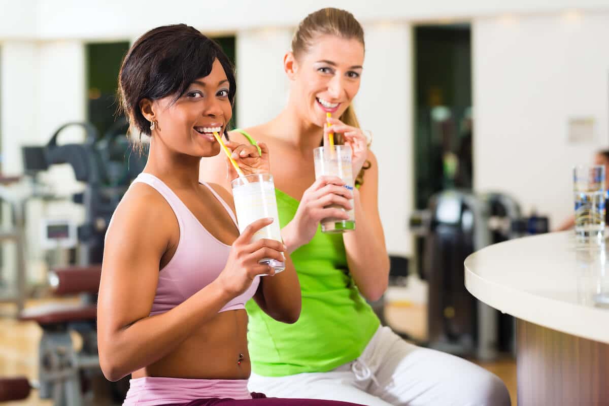 Two women looking at the camera while sipping their drinks