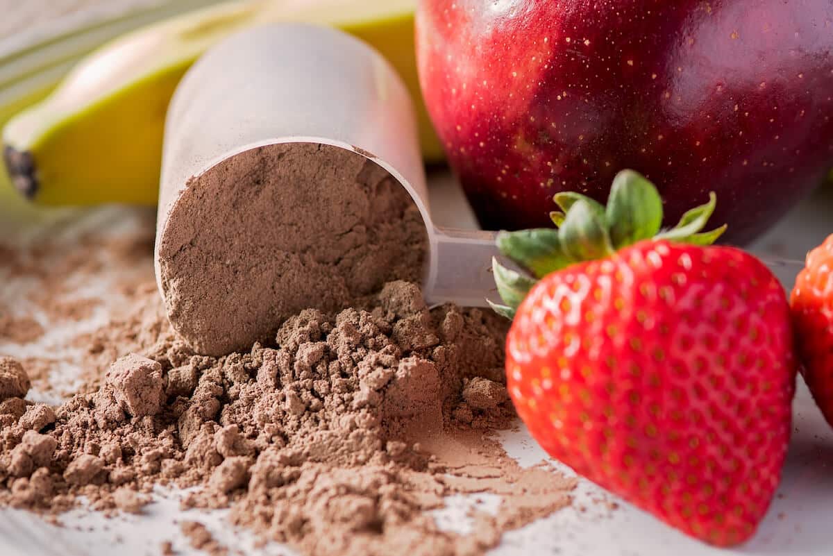 Protein powder, strawberries, apple, and a banana