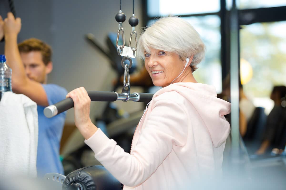 Supplements for building muscle after 60: senior woman working out at a gym