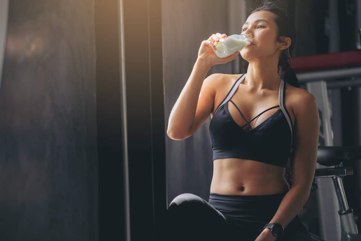 How many protein shakes a day: woman drinking some protein shake from her tumbler