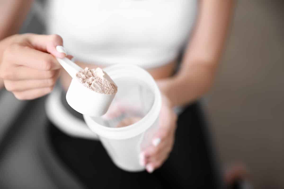 Person pouring protein powder into a tumbler