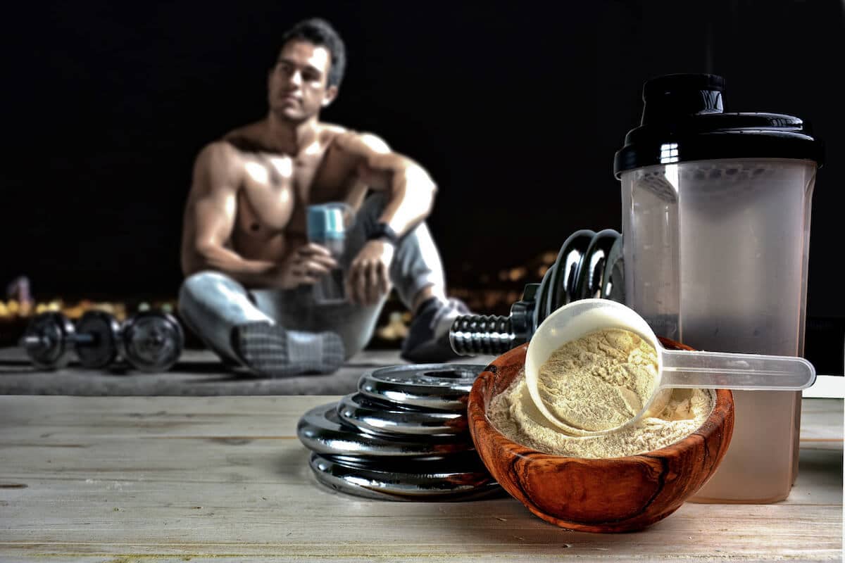 Best supplements for muscle growth: protein powder in a bowl and a man sitting on the floor
