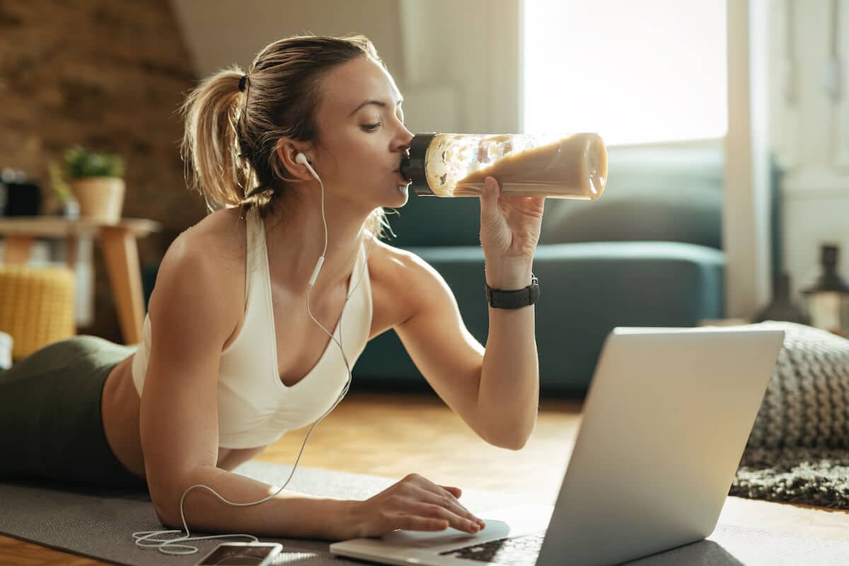 Woman drinking from her tumbler while using a laptop