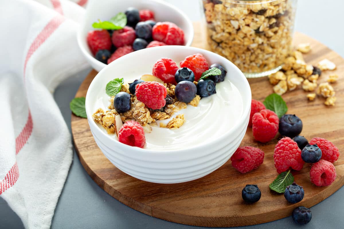High protein breakfast: yogurt with berries, granola, and mint leaves